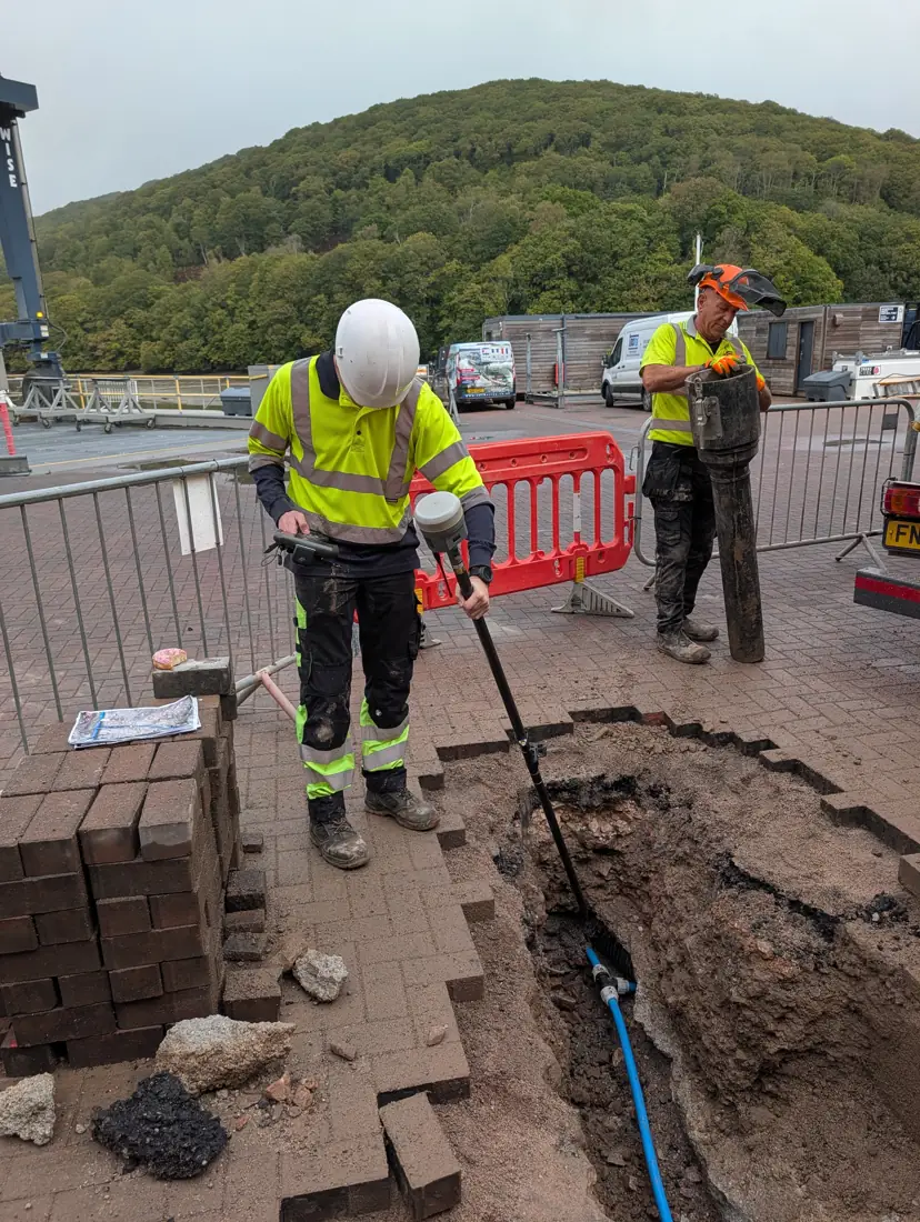 Surveyor recording an exposed service with a GNSS pole