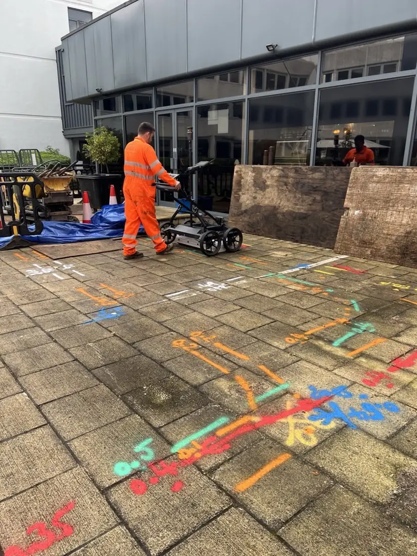 Surveyor pushing a GPR cart across colour-coded service markings