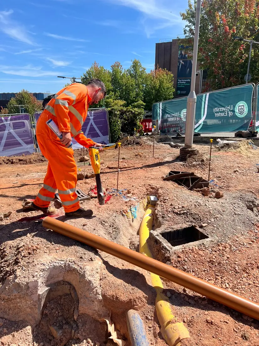 Surveyor using an electromagnetic locator beside exposed services