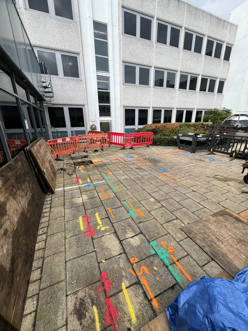 Colour-coded service markings across a paved courtyard